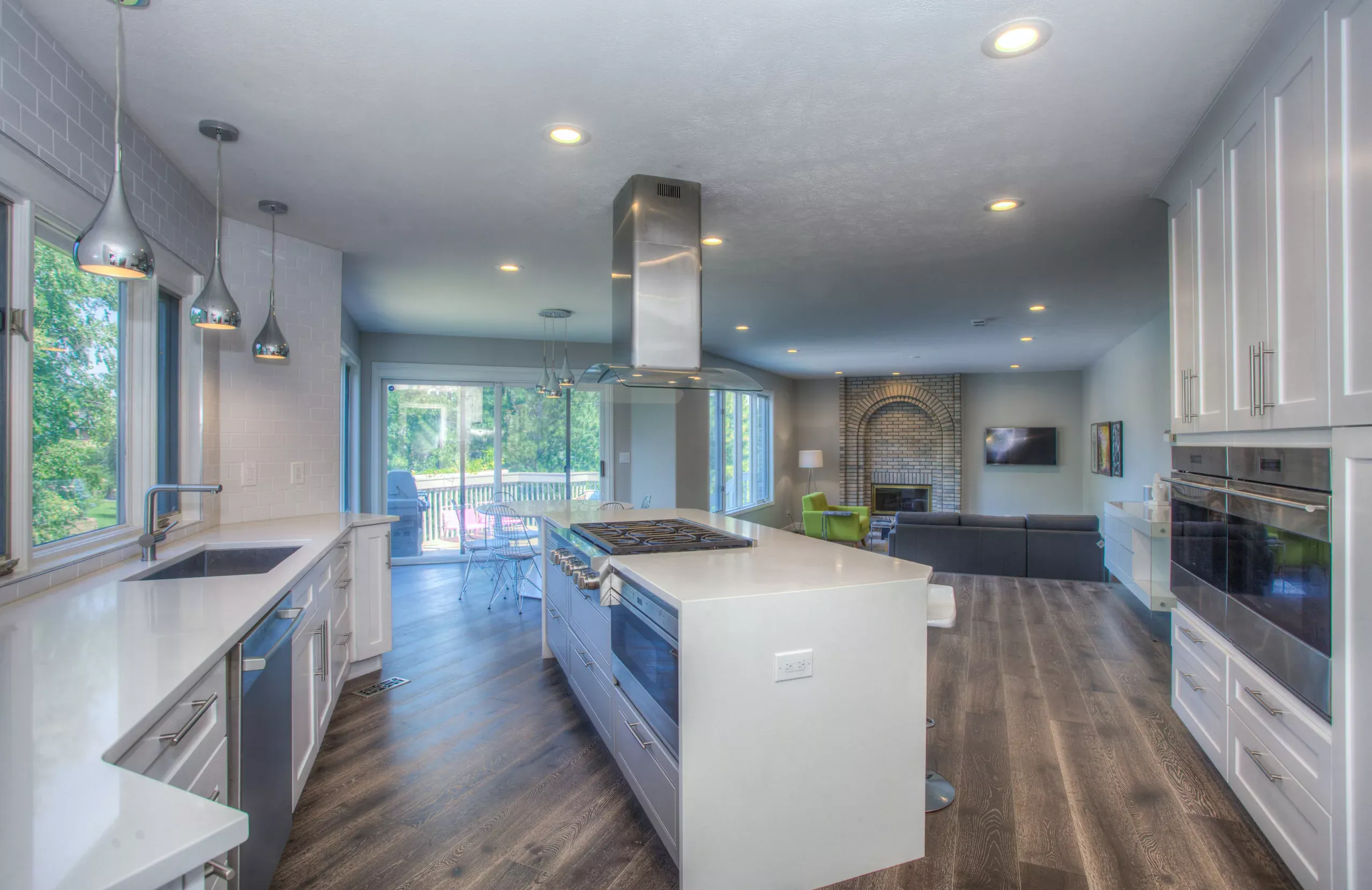 Modern kitchen with white shaker cabinetry, large white island with waterfall edge, stainless steel appliances, wood plank
