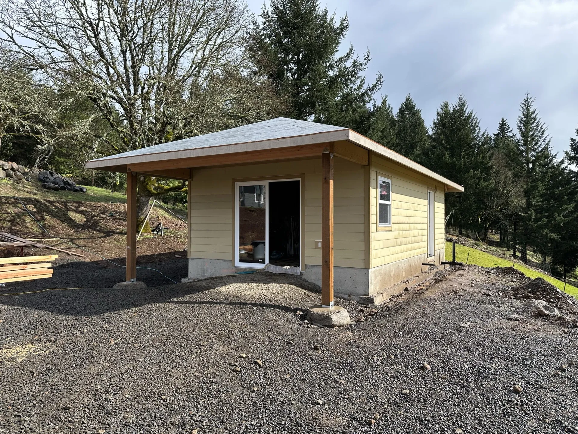 Finished small residential building by Boss PDX with tan siding, metal roof, and covered entry porch