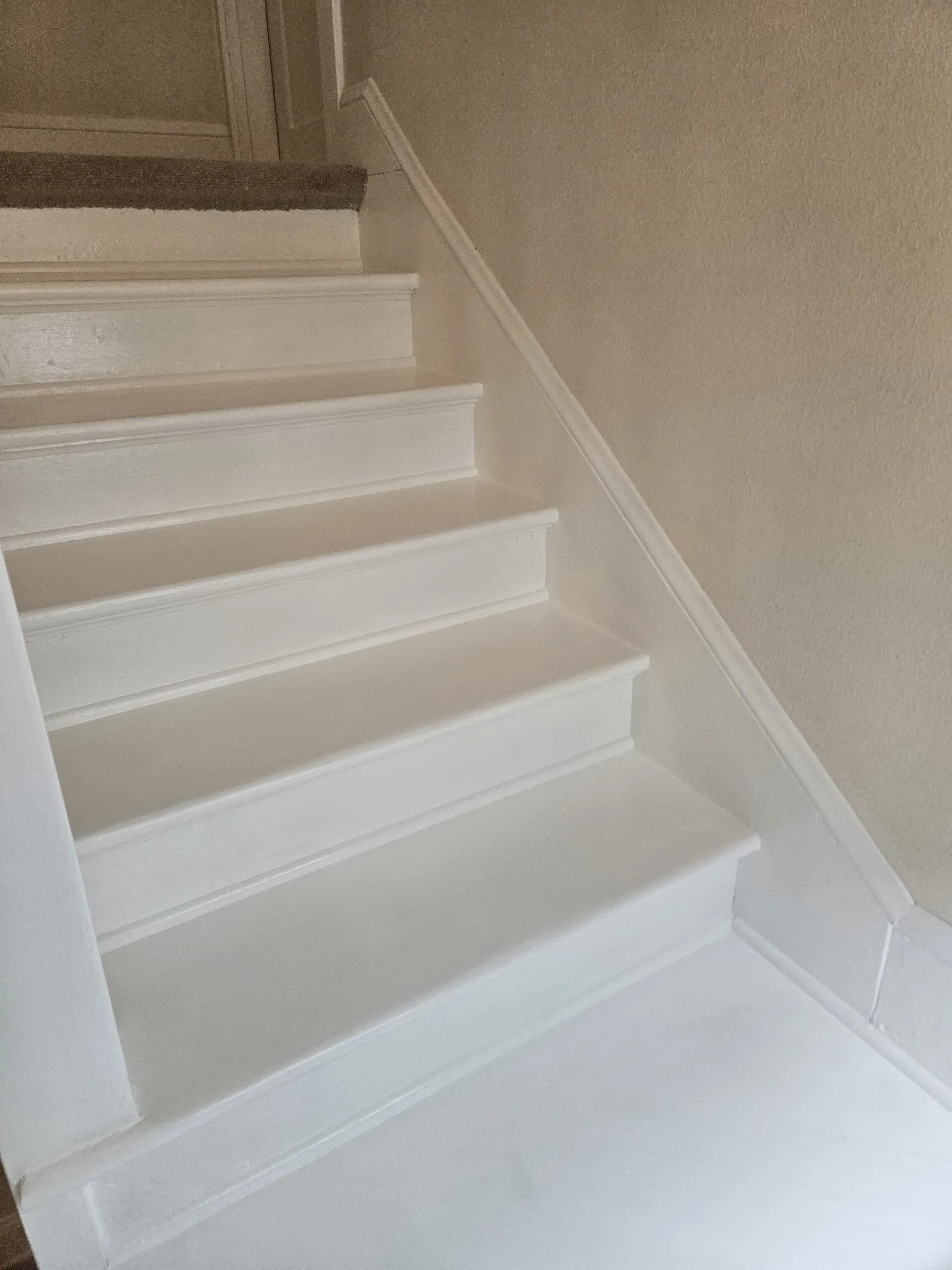 White painted wooden staircase with evenly spaced treads and risers, viewed from above, showing clean finish and white