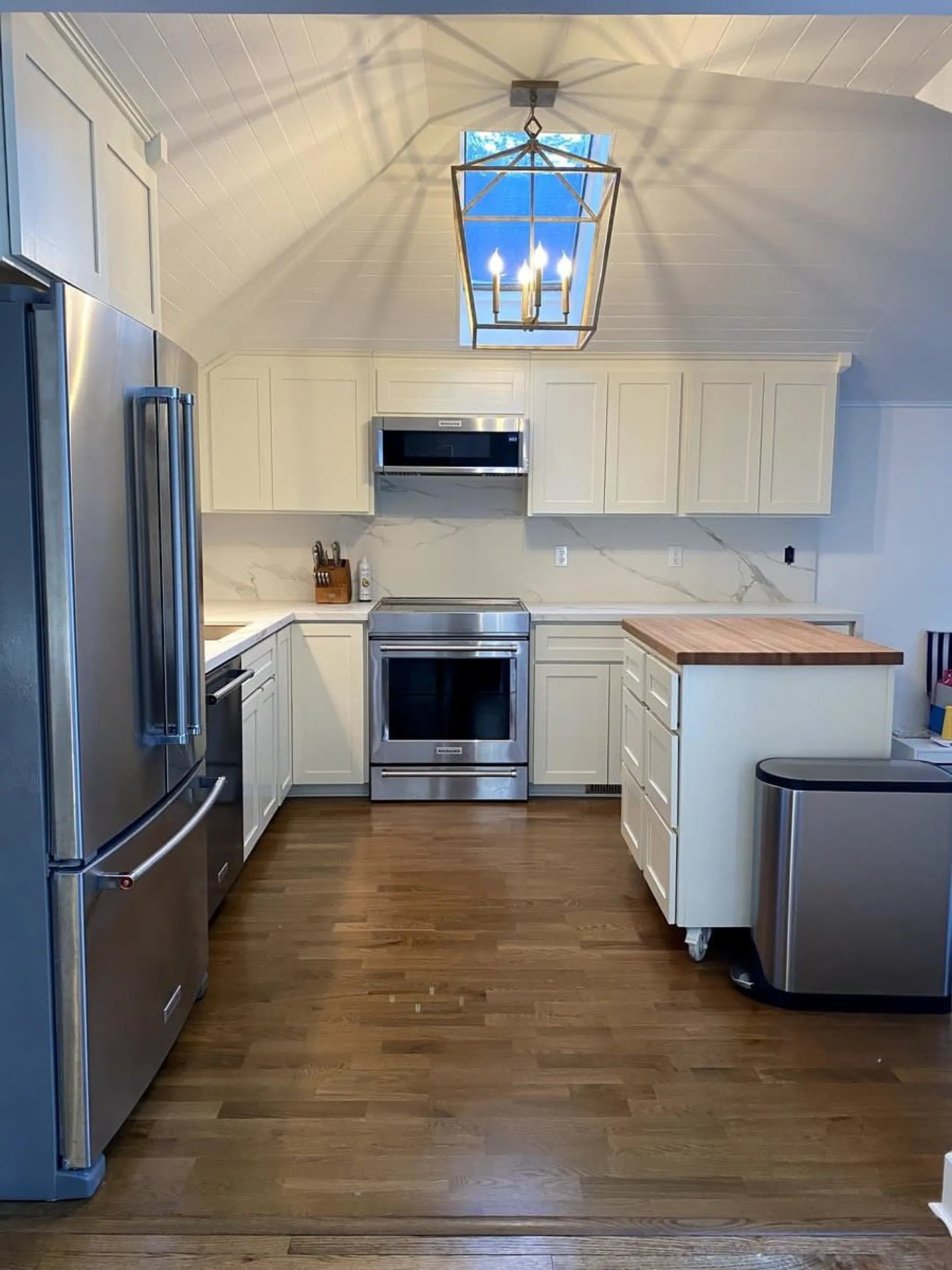 Finished modern kitchen remodel by Boss PDX with white shaker cabinetry, stainless appliances, and wood island top