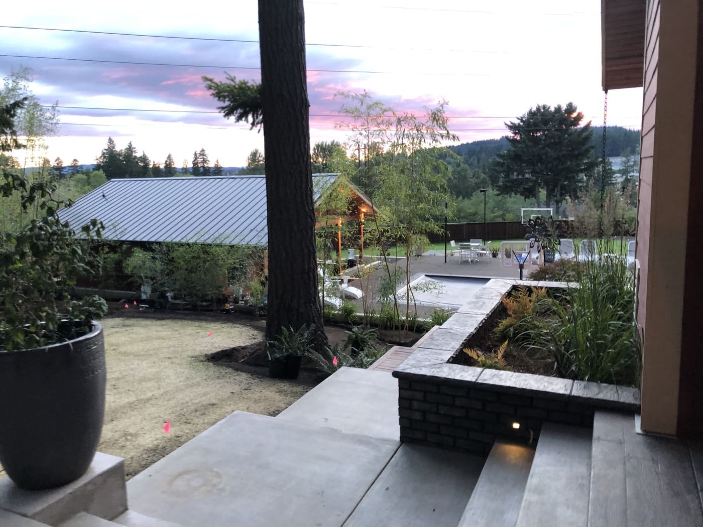 Patio with stone planters and sport court at sunset